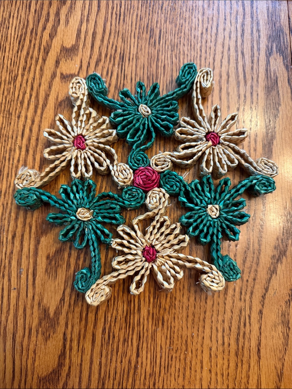 Vintage woven trivet floral design made from raffia straw in green, tan, and red